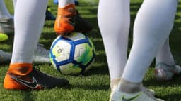 Jogadores disputam a bola durante partida de futebol da Série B, com foco nas pernas e chuteiras dos atletas