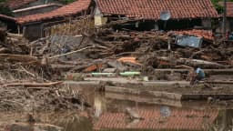 Casas destruídas por enchente no Vale do Ribeira, em São Paulo, com morador sentado entre os escombros (imagem de arquivo)