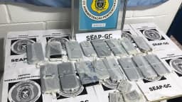 Celulares e outros materiais apreendidos em unidade prisional, organizados sobre mesa com etiquetas de identificação
