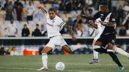 Jogador do Fluminense, de camisa branca com faixas verde e grená, finaliza a gol marcado por um atleta do Vasco, de camisa preta com faixa branca, no gramado do Maracanã