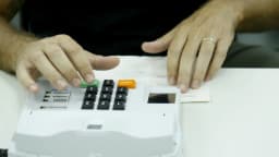 Mãos de eleitor digitando em urna eletrônica durante votação