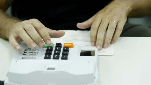 Mãos de eleitor digitando em urna eletrônica durante votação
