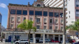 Rua do centro histórico de Santos (SP), com prédio antigo e movimento de carros