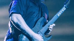 Integrante do Slipknot com máscara característica tocando guitarra em show