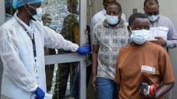 Profissional de saúde com máscara e luvas atende pessoa durante triagem de ebola