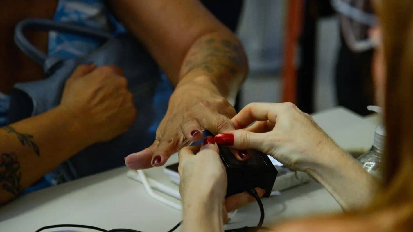 Mãos de eleitor e de atendente da Justiça Eleitoral durante coleta de dados biométricos em posto do TRE