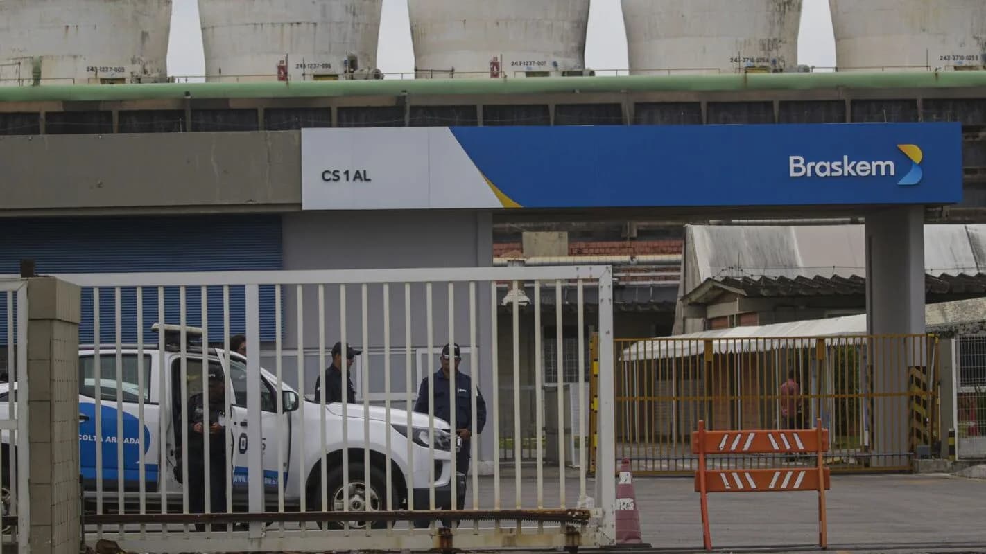 Fachada de unidade industrial da Braskem, com logo da empresa e viatura estacionada em frente ao portão