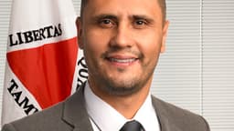 Retrato oficial do senador Cleitinho, de terno cinza, sorrindo, com a bandeira de Minas Gerais ao fundo