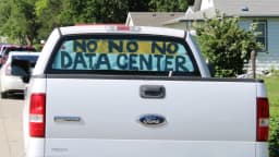 Caminhonete com cartaz pintado à mão nos vidros traseiros dizendo 'No, no, no data center', em protesto contra a instalação de um data center em bairro rural do Kansas, EUA