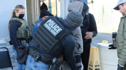 Agentes do ICE, com coletes identificados como 'POLICE' e 'ICE', durante operação de detenção nos Estados Unidos