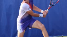 João Fonseca em quadra durante partida de tênis, preparando um golpe de backhand