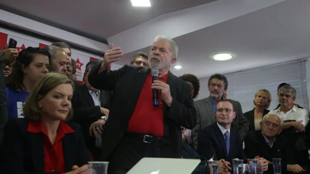 Presidente Lula fala ao microfone ao lado da senadora Gleisi Hoffmann em evento do PT