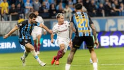 Jogador do Fluminense conduz a bola sob marcação de dois jogadores do Grêmio durante partida na Arena, em Porto Alegre
