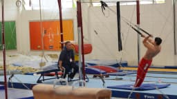 Ginasta brasileiro treina nas argolas em ginásio, observado por técnico (imagem de arquivo, 2016, preparação para os Jogos Olímpicos do Rio)