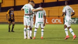 Jogadores da Chapecoense em uniforme branco se abraçam em comemoração durante partida de futebol