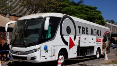 Ônibus itinerante do TRE-MG estacionado em via pública, com a inscrição "TRE Aqui" e o brasão da Justiça Eleitoral