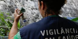Agente de vigilância em saúde inspeciona garrafa com água parada em busca de foco do mosquito Aedes aegypti