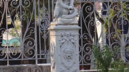 Portão de ferro ornamentado com estátua na entrada do Espaço Cultural Palácio Potengi, antiga sede do governo do Rio Grande do Norte, em Natal
