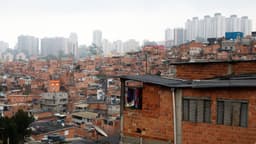 Vista da comunidade de Paraisópolis, com casas de alvenaria sem reboco e prédios altos do Morumbi ao fundo, em São Paulo; imagem de arquivo