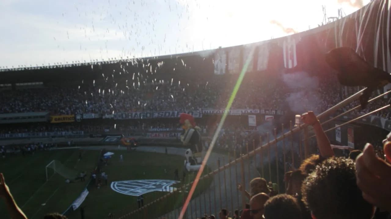 Torcida em estádio lotado com bandeiras e fumaça colorida, foto de arquivo de clássico mineiro
