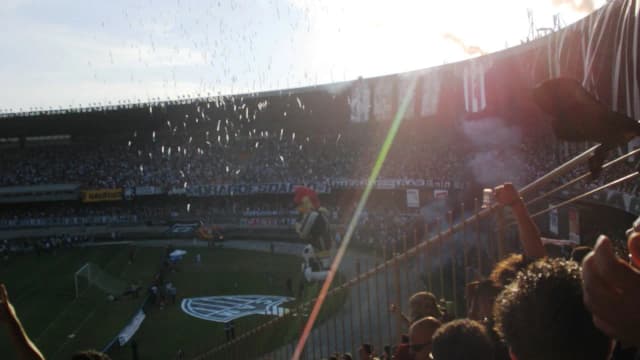 Torcida em estádio lotado com bandeiras e fumaça colorida, foto de arquivo de clássico mineiro