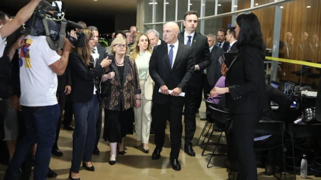 Alexandre de Moraes caminha em corredor cercado por assessores e jornalistas em coletiva de imprensa