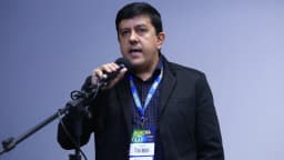 Prefeito mineiro discursa em microfone durante Marcha dos Prefeitos em Brasília, com crachá de identificação da prefeitura
