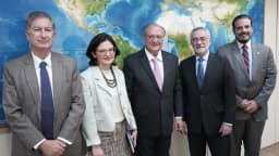 Vice-presidente Geraldo Alckmin em reunião oficial, ao lado de outras autoridades, diante de um mapa-múndi
