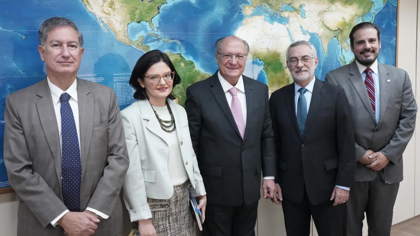 Vice-presidente Geraldo Alckmin em reunião oficial, ao lado de outras autoridades, diante de um mapa-múndi