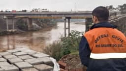 Agente da Defesa Civil do Rio Grande do Sul observa rio cheio em foto de arquivo