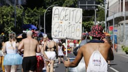 Vendedor ambulante carrega cartaz "Aceito cartão" durante bloco de carnaval no Rio de Janeiro, foto de arquivo