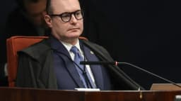 Ministro Cristiano Zanin sentado à mesa de sessão do STF, de toga, olhando para o lado