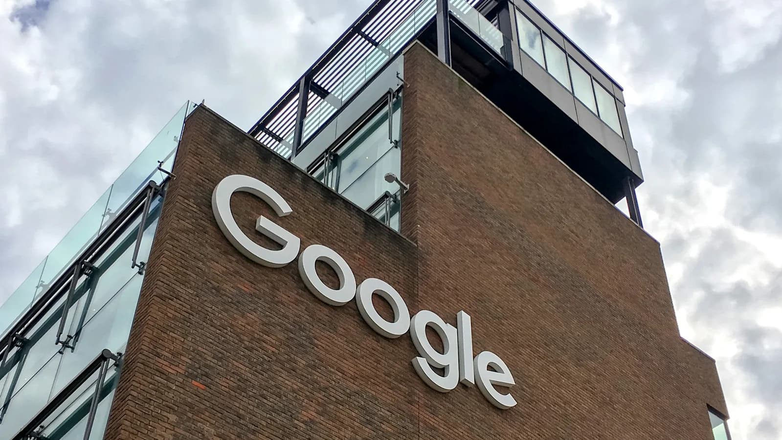 Fachada de prédio com o logotipo do Google em destaque, sob céu nublado.