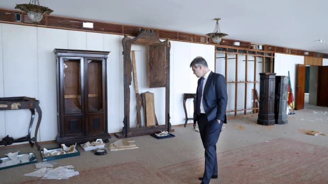 Ministro André Mendonça caminha por sala do STF em meio a móveis danificados