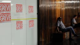Cartazes com os dizeres 'bancários em greve' colados em agência bancária, com pessoas esperando no saguão, foto de arquivo