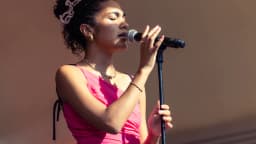 Olivia Dean canta ao microfone durante apresentação ao vivo