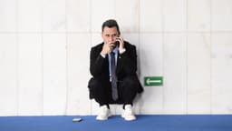 O senador Cleitinho, agachado e encostado em uma parede de mármore, fala ao celular em um corredor do Senado; imagem de arquivo