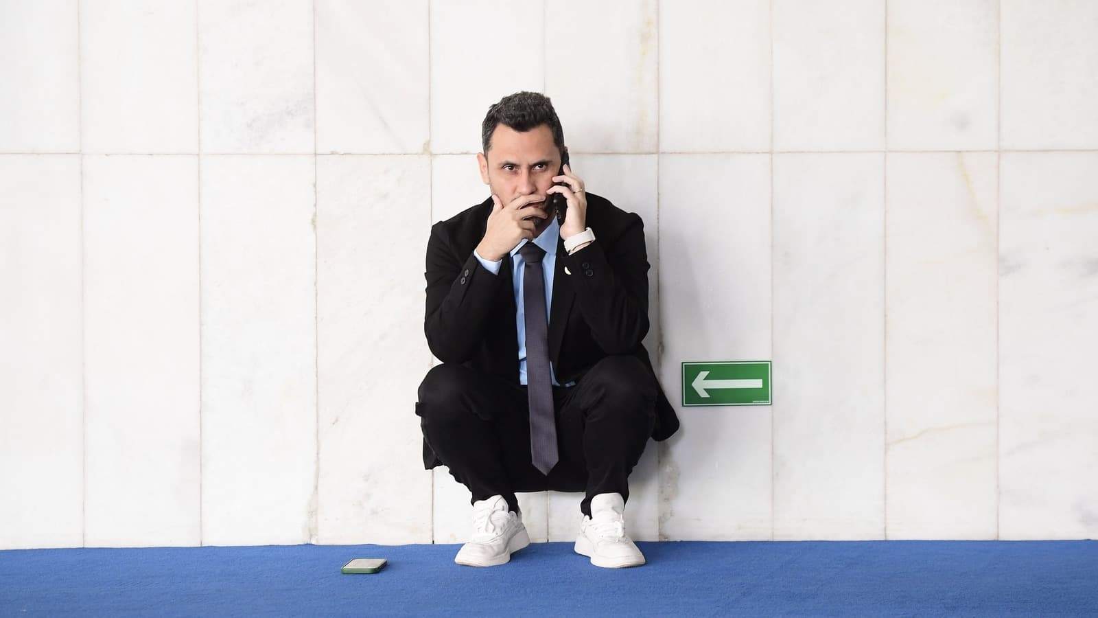 O senador Cleitinho, agachado e encostado em uma parede de mármore, fala ao celular em um corredor do Senado; imagem de arquivo