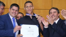 Richarlison segura placa de homenagem ao lado de deputados na Assembleia Legislativa do Espírito Santo (foto de arquivo)
