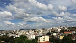 Vista aérea de Divinópolis (MG), com prédios e casas da cidade sob céu parcialmente nublado