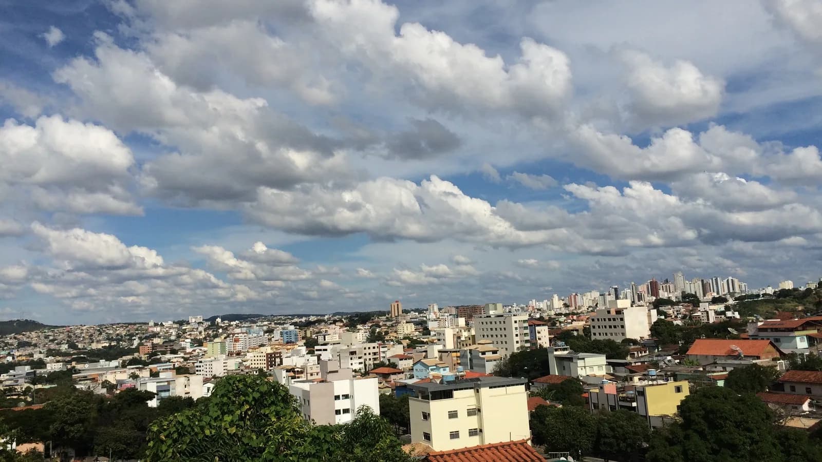 Vista aérea de Divinópolis (MG), com prédios e casas da cidade sob céu parcialmente nublado