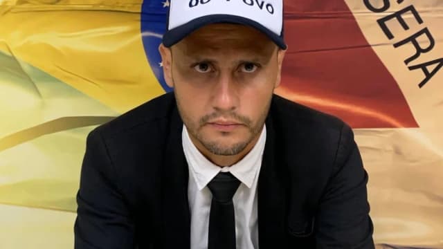 Retrato do senador Cleitinho Azevedo, candidato ao governo de Minas Gerais, vestindo boné de campanha e terno escuro