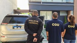 Agentes da Polícia Federal e da Controladoria-Geral da União durante operação, de costas, com viatura ao fundo