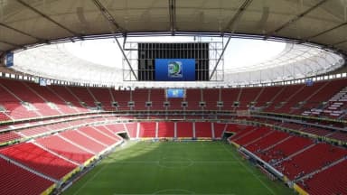 Interior do estádio Mané Garrincha, em Brasília, vazio, com telão exibindo logotipo do Brasil 2013