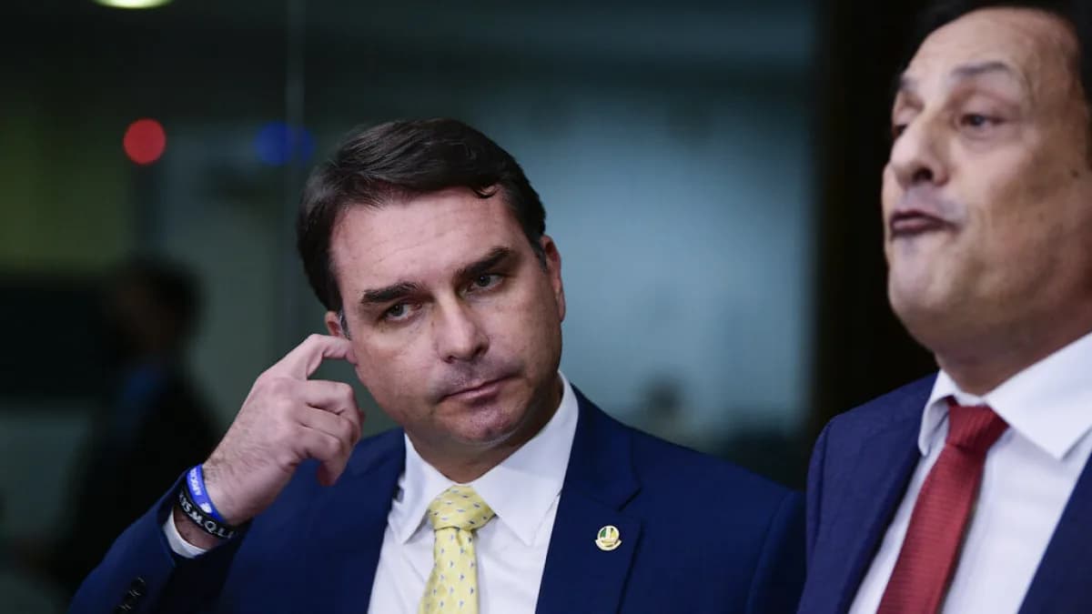 Flávio Bolsonaro fala à imprensa em frente a microfones de rádio e TV
