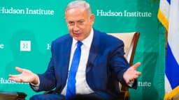 Benjamin Netanyahu gesticula durante entrevista, com bandeira de Israel ao fundo