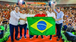 Imagem de arquivo: o presidente Lula, de camisa vermelha e chapéu de palha, segura uma bandeira do Brasil ao lado de aliados no palco da convenção da Federação Brasil da Esperança no Ceará, em 31 de julho, diante de um ginásio lotado