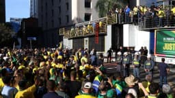 Multidão reunida em ato político em via pública de São Paulo, com faixas e bandeiras, cena semelhante às manifestações citadas no alerta britânico