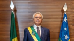 O governador Ronaldo Caiado, de terno azul e faixa de governador de Goiás, ao lado das bandeiras do Brasil e de Goiás, em foto de arquivo de 2023