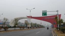 Pórtico vermelho de entrada da Zona de Livre Comércio de Hunan, na China, sobre uma avenida